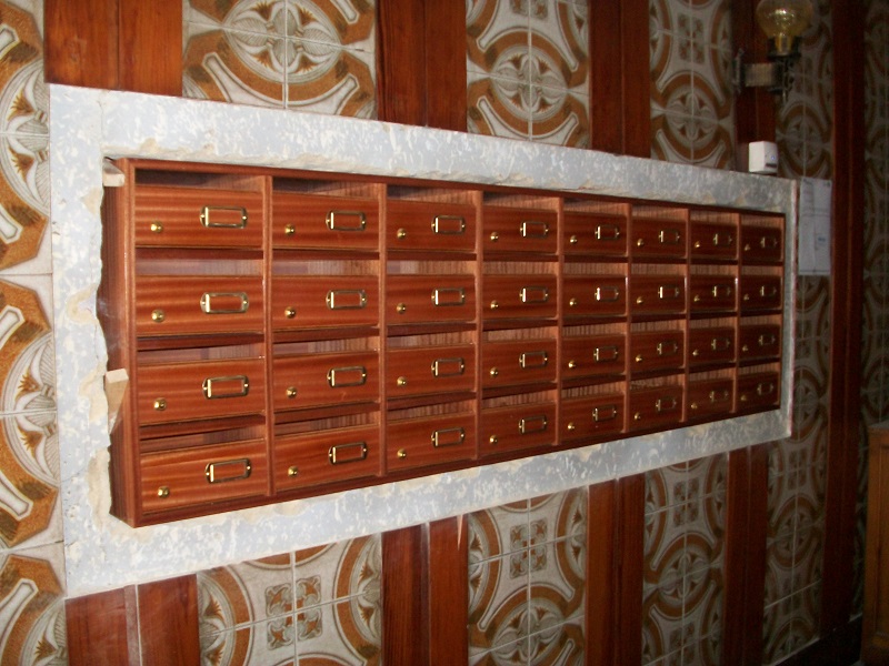 Agrupación de buzones Medina fabricados en madera de Sapelly colocados en el hueco disponible en la comunidad.